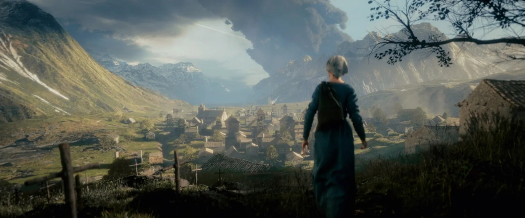 A lone figure looks down toward a mountain village.