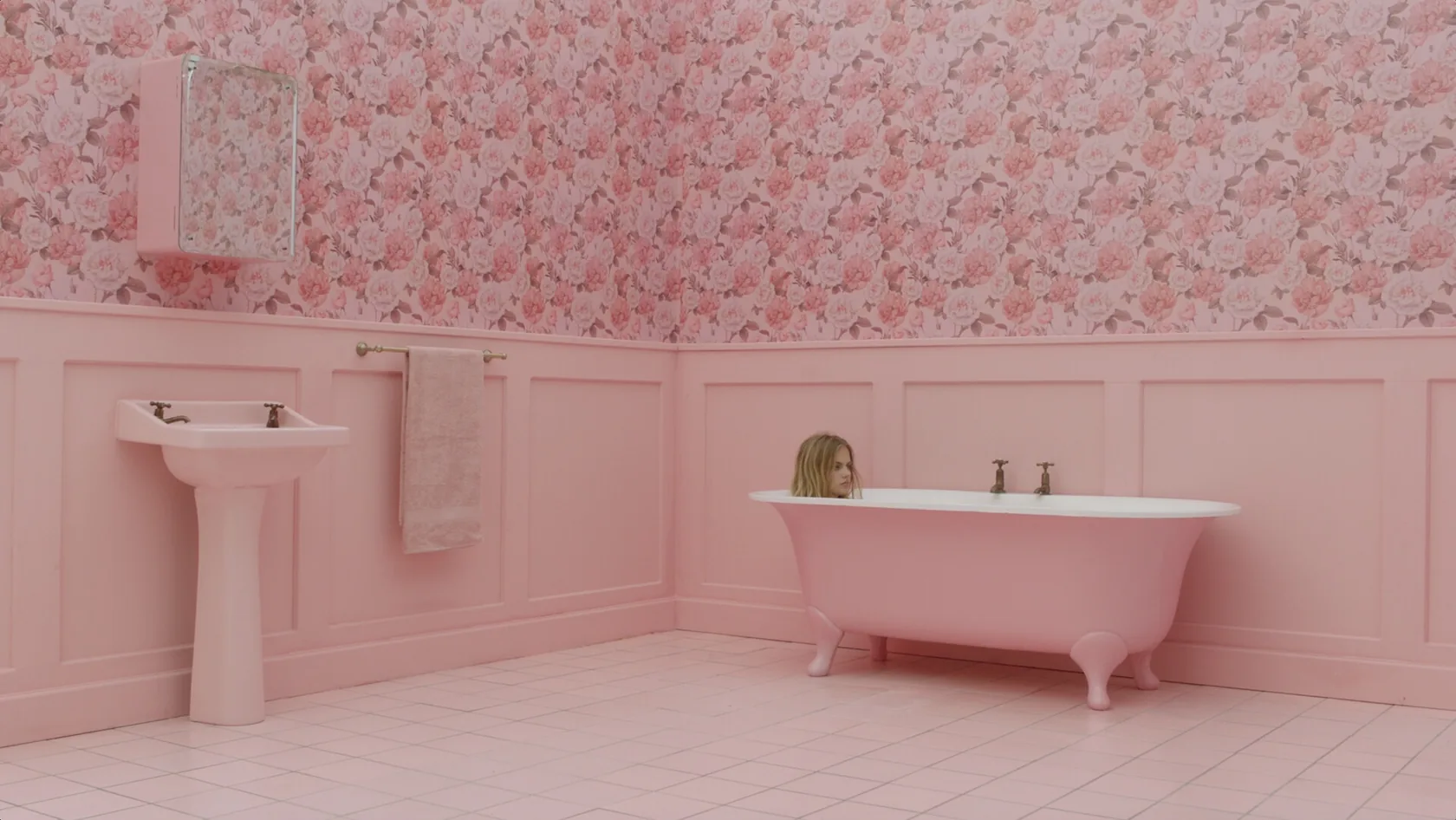 A surreal pink bathroom with a woman in a bathtub.